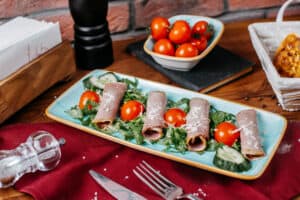 involtini di prosciutto cotto su letto di rucola e pomodorini