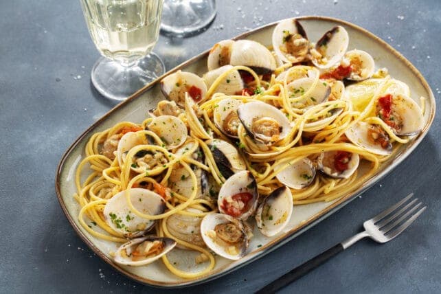 piatto di spaghetti allo scoglio accompagnati da vino bianco